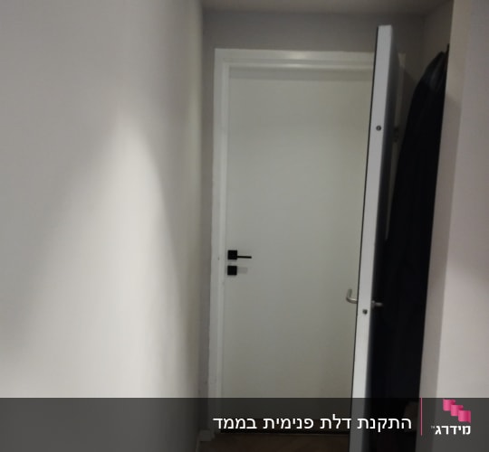 דלת לבנה פתוחה עם ידית שחורה